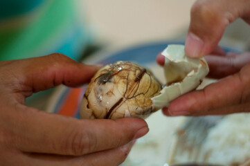 Close up photo of hands peel away a Balut, or fertilized duck egg, before eating it. It is popular street food in the Philippines.
