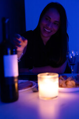 Woman having a glass of wine on a romantic candlelit date.