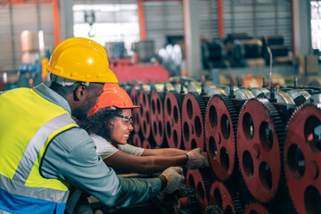 Female engineer hand trap in big machinery gears factory accident. Male colleague help, demonstrate quick response teamwork. Both wear safety helmet and vest,Industrial workplace,emergency, assistance