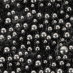 Seamless 4k photo texture material of black patterned and polished leather surface with rivets.