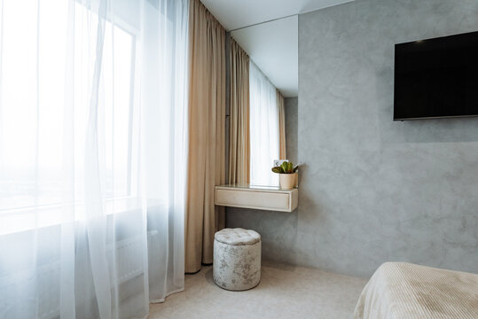 The bedroom features a comfortable bed for sleep, an elegant ottoman for relaxation, a modern TV for entertainment, and a stylish mirror, all creating a cozy and inviting atmosphere