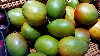 Fresh Mangoes Displayed in a Wicker Basket at a Local Market During a Sunny Afternoon
