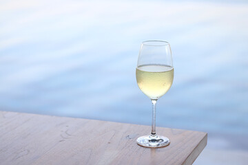 glass of cold white wine on the summer seashore by the water, relaxing by the water, a gentle...