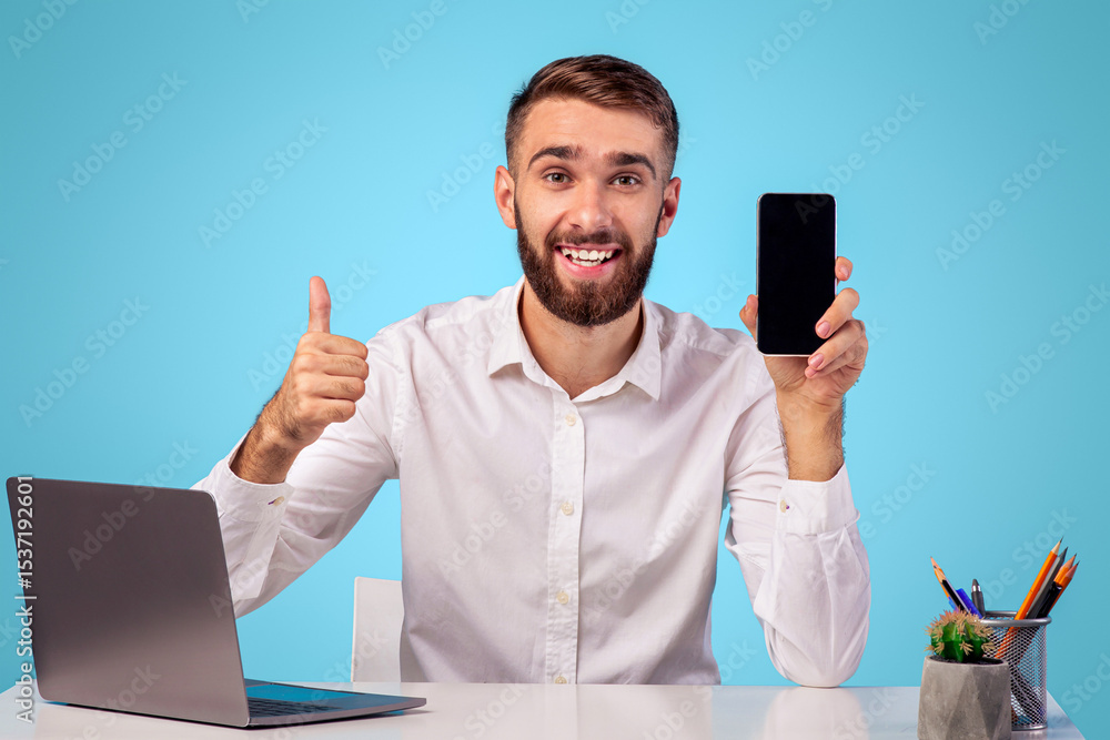 Poster positive young office employer showing smartphone with empty screen and showing thumb up gesture at 