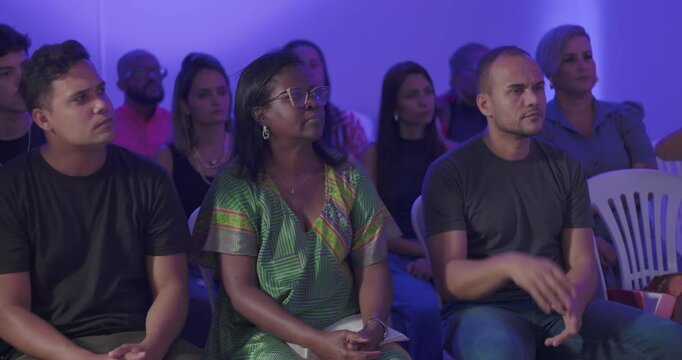 Hispanic and Latin congregation seated in reverent silence at evangelical service, African American woman in center with closed eyes and composed expression