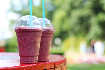 Berry milkshake with ice cream. Summer drink in disposable plastic cup with straw. Coffee with ice...