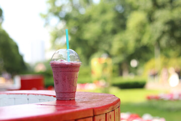 Berry milkshake with ice cream. Summer drink in disposable plastic cup with straw. Coffee with ice...