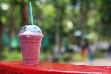 Berry milkshake with ice cream. Summer drink in disposable plastic cup with straw. Coffee with ice...