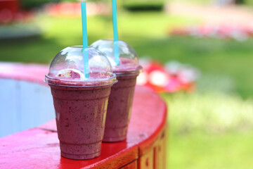 Berry milkshake with ice cream. Summer drink in disposable plastic cup with straw. Coffee with ice...