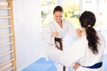 Obraz premium Two women in kimono sparring together in gym during karate training