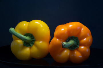 Yellow and orange  bell peppers against a black background.