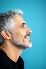 Obraz premium Visual idea of style for aging men. Trendy men's textured crop haircut - midlife arabian man with short hair. A confident man making a stylish impression. Blue solid background.