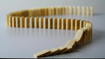 Finger pushing domino line destroying wavy shape on light table surface closeup. - Powered by Adobe