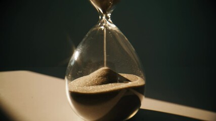 Closeup sand falling hourglass standing at table in evening room. Gold grains - Powered by Adobe