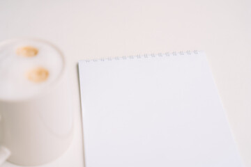 Spiral notepad and cup of coffee with creamy foam on a white minimal background. High quality photo