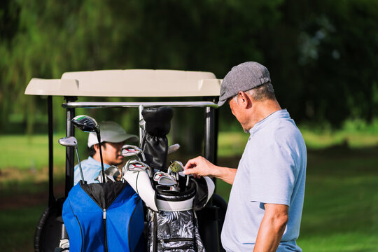 Senior Golfer Choosing Golf Club from Bag on Beautiful Fairway Lawn During Morning Light. Ideal for Active Aging, Retirement Lifestyle, and Outdoor Sport Concepts.