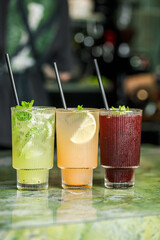 Refreshing cocktails lined up on a green marble bar ready for enjoyment in a lively atmosphere