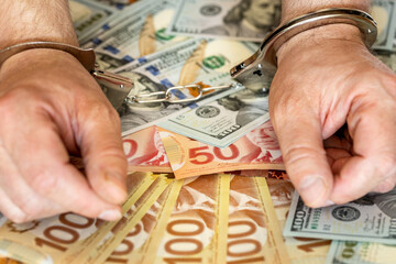 Crime in Canada. Hands handcuffed with Canadian and American dollars in the background. Concept....
