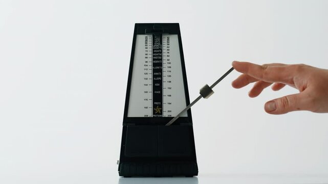 Musician hand adjusting metronome on white desk closeup. Tempo tool swinging 