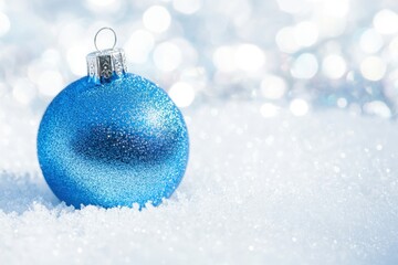 Fototapeta premium Sparkling Blue Christmas Ornament in Snow with Festive Bokeh Background.