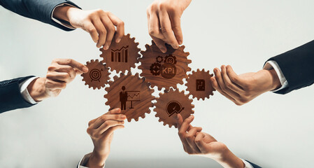 A group of hands working together to manipulate wooden gears, each representing essential business...