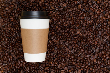 Disposable coffee cup standing on roasted coffee beans