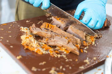 Person Slicing Cooked Meat on a Cutting Board.