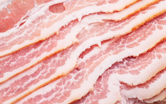 Slices of uncured pork belly or becon slices close up.