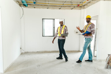 Two construction workers in safety gear inspect and discuss progress inside an unfinished building....