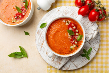 Spanish cool soup Andalusian gazpacho in a white plate with basil, is a cold soup made of raw, blended vegetables, tomatoes, bell pepper,  cucumber, vinegar, garlic and stale bread. Directly above.