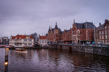 Amsterdam, Netherlands. The city's waterfront is lined with moored boats, creating a charming scene alongside countless bicycles and elegant buildings that offer picturesque views of the canals.