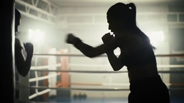 Woman power, silhouette of slender lady in boxing ring, training with punch bag. Active lifestyle and sport for stay healthy