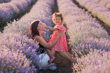 Mother and daughter in in purple lavender field in summer at sunset. Motherhood. Mother's day