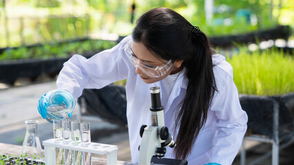Scientist examining plants on an organic farm while holding research equipment. Conducting quality...
