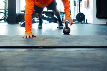 Athlete doing push-ups with kettlebell in modern gym