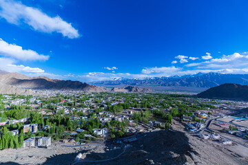 scenic view of Leh City nestled among rugged mountains, with snow-capped peaks in the distance ...