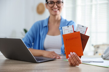 Travel agent with passports and tickets at wooden table in office, selective focus