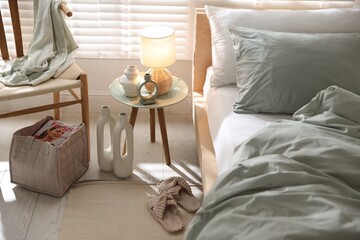 Comfortable bed with soft linens, lamp and decor in stylish room. Home textile
