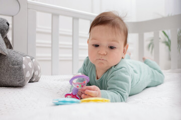 Naklejka premium Cute little baby with rattle toy in crib at home