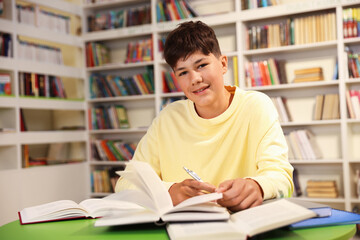 Student with books studying at table in library