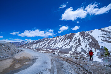 A breathtaking view of rugged mountain peaks snow beneath a vivid blue sky scattered with soft...