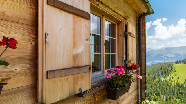 The window of wooden chalet in the Swiss Alps with colorful geraniums - Powered by Adobe