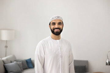 Happy homeowner. Portrait young adult Arabic man dressed in traditional white Islamic attire with...