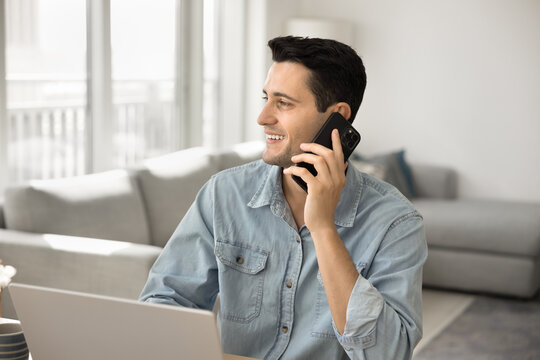Multitasking professional. Busy gen z male self employed entrepreneur salesman freelancer engaged in remote job discuss customer order give advice consultation by phone distracted from notebook screen