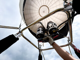 Hot air balloon launch preparation with gloved hand adjusting burners
