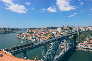 Obraz premium orange rooftops panorama of the old town of porto and duoro river on blue sky day and iron famous eiffel bridge