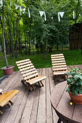A serene outdoor relaxation area on a wooden deck, featuring rustic wooden lounge chairs under a...