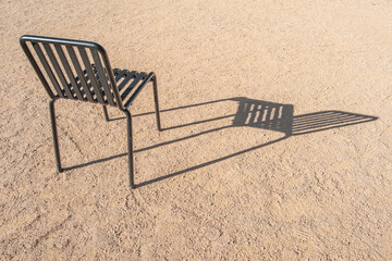 Green iron chair casting its shadow, isolated, in a garden
