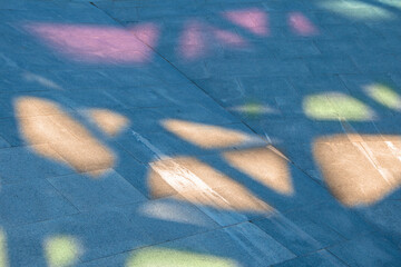 Cement floor with colored shadows and lights projected by stained glass in a square