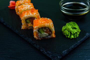 Sushi roll philadelphia with salmon, rice, cheese, cucumber, avocado and caviar on a slate board. Japanese food